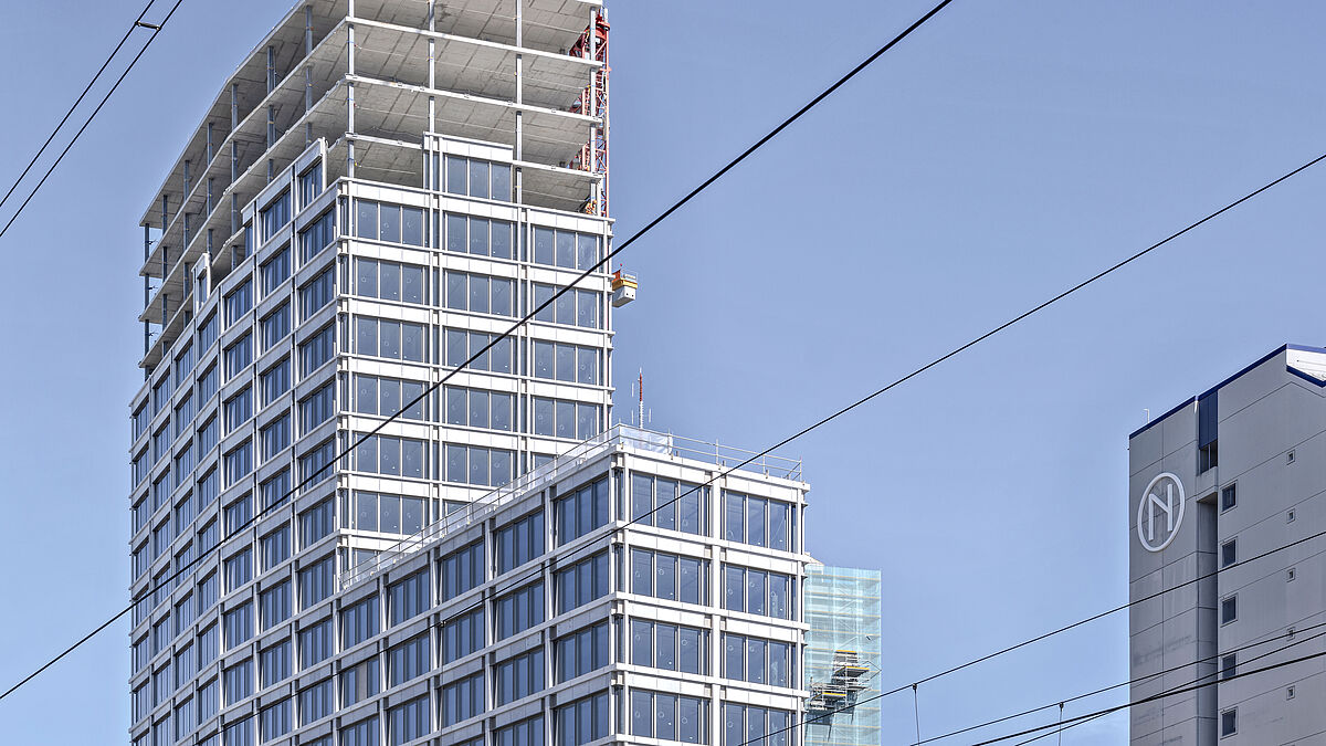 Dicht an den Gleisen prägt der neue, 21-geschossige, abgestufte Baukörper die Skyline von Zürich Oerlikon. 