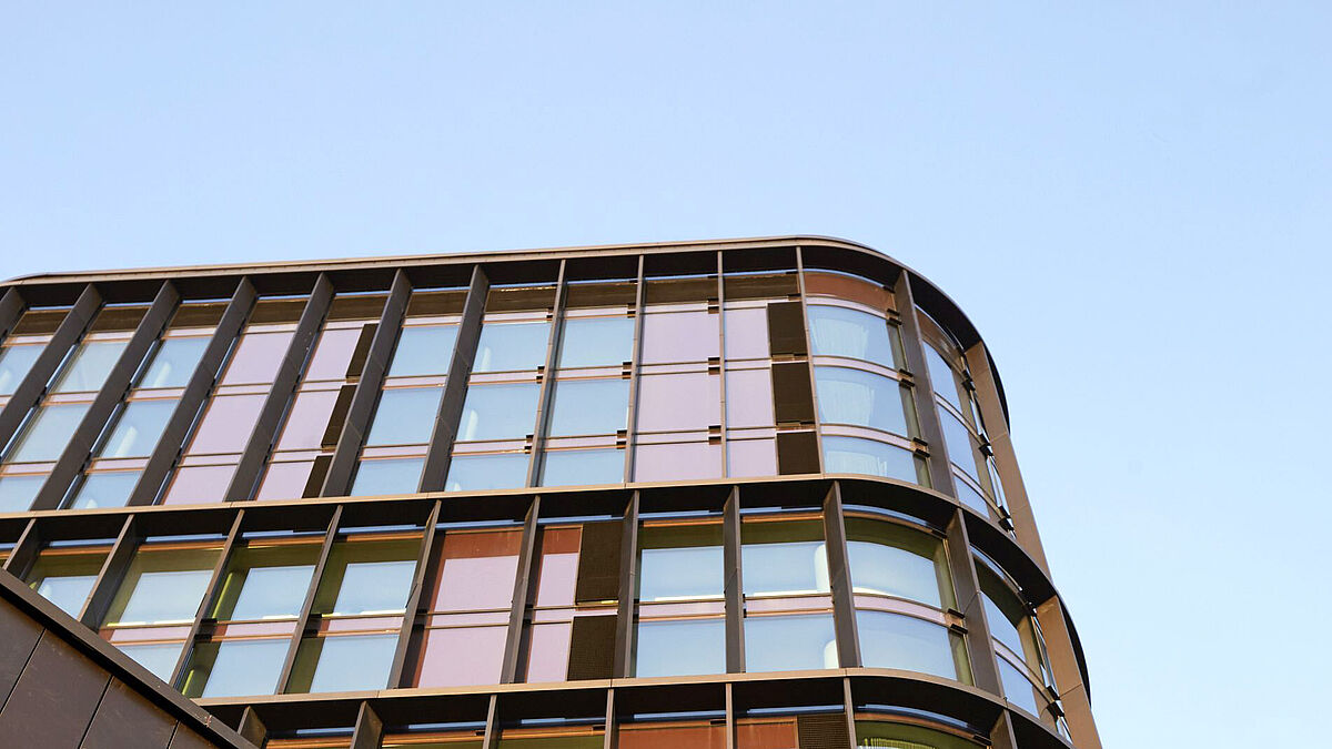 Die Fassaden sind mit Fensterformaten unterteilt, welche die Vertikalität betonen. Sie wirken plastisch und mit Tiefe, sodass sie von allen Seiten als Relief wahrgenommen werden. Die vertikalen Kupferlamellen unterstützen diese dynamische Fassadenstruktur. 