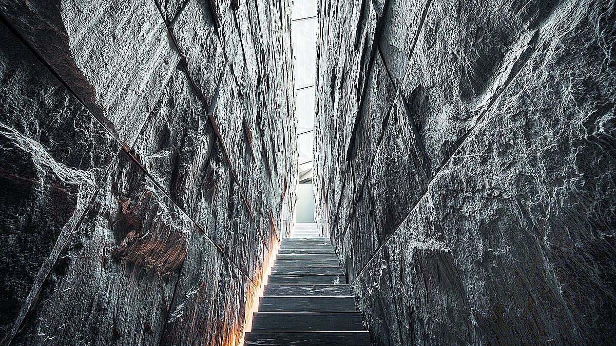 Bild: Daniela DerungsBlick in die diagonal durch das Gebäude führende Felsspalte mir der hinterleuchteten Steintreppe.