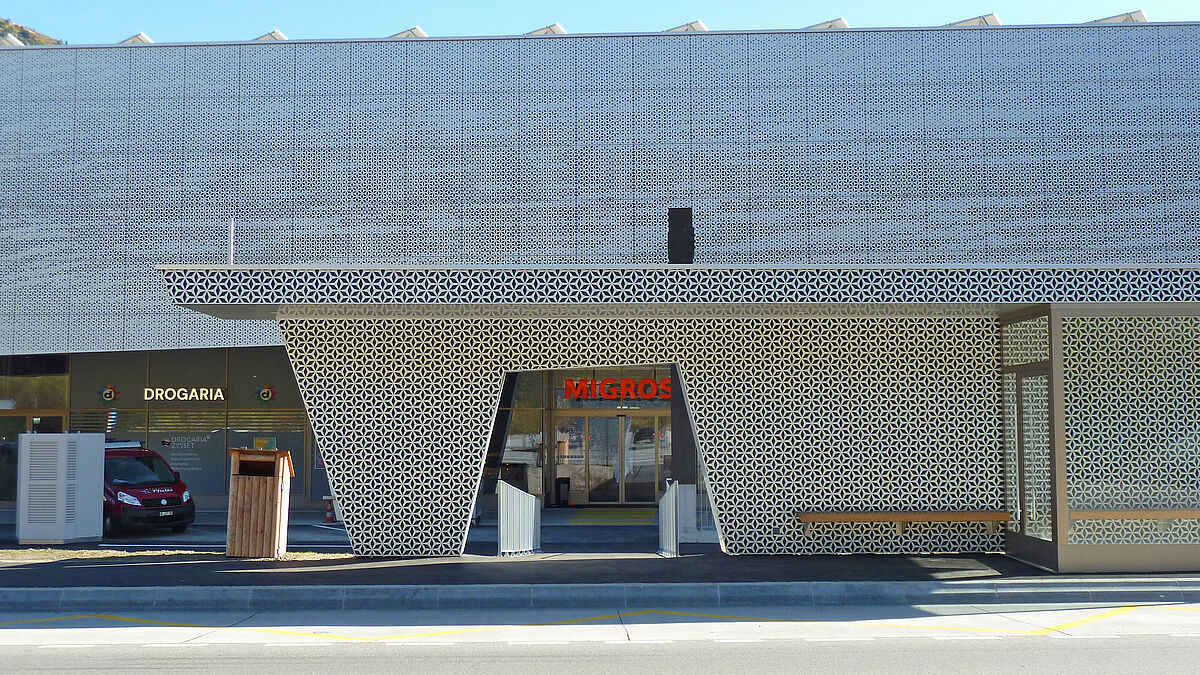 L’abribus reprend la forme et le style de la façade au second plan.