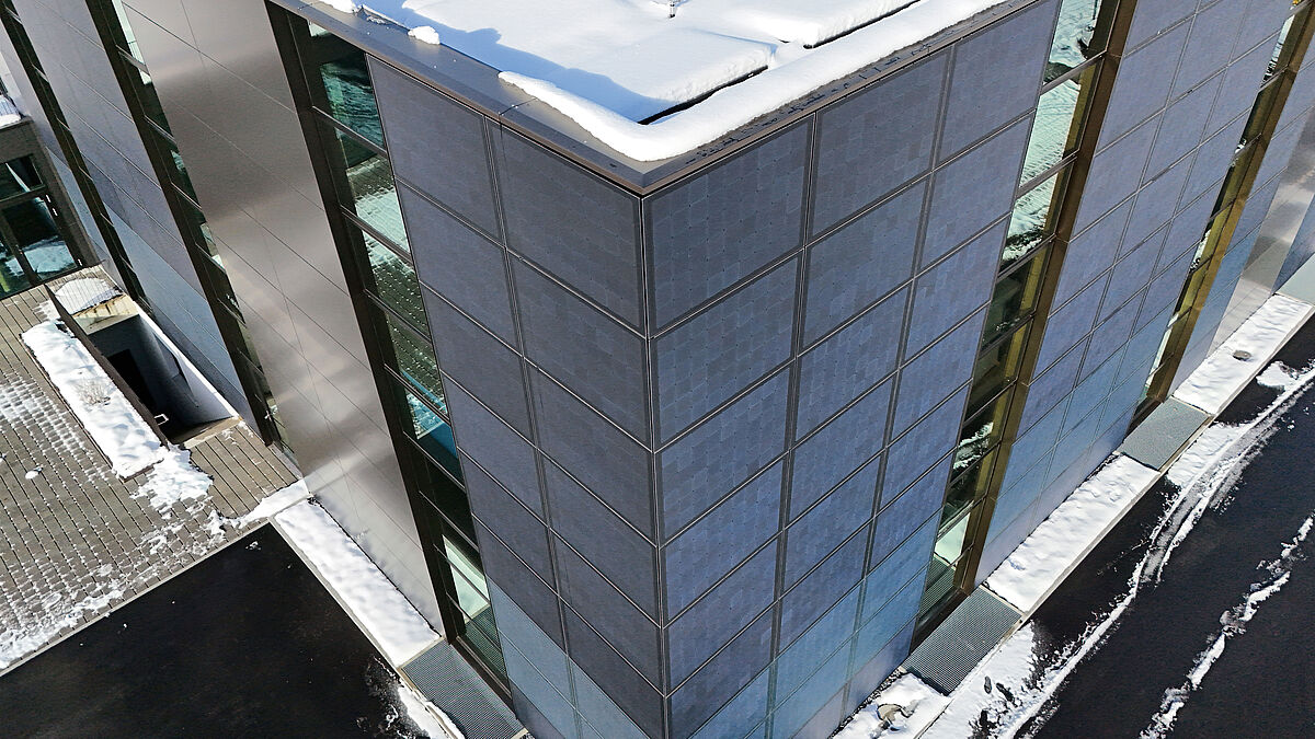 Les modules photovoltaïques, visibles ici dans l’angle, se confondent avec les revêtements Alucobond situés à gauche du bandeau de fenêtre.