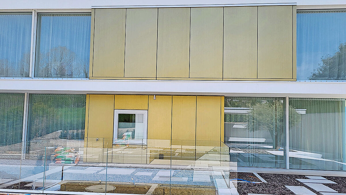 Gebäude-Bergseite: Während die seitlichen Gebäudeflanken transparent, mit hohem Glasanteil ausgebildet sind, ist die Aussenhaut im Bereich des Gebäudekerns als hinterlüftete Blechfassade ausgeführt.