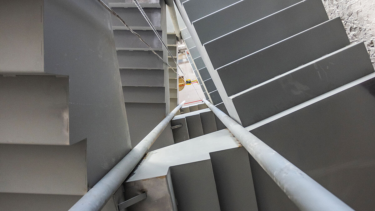 Vue du bas vers le haut : la forme triangulaire ou en goutte du jour de l’escalier et la disposition des poteaux en acier sont bien visibles.