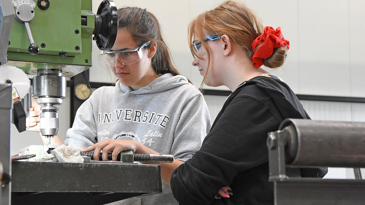 Angehende Metallbaukonstrukteurinnen bohren Löcher für die Hinweistafeln.