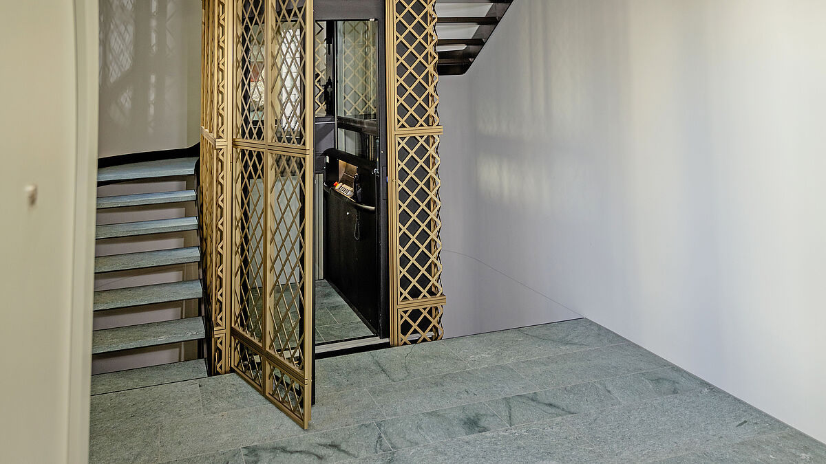 Dans le hall d’entrée, l’ascenseur vitré revêtu d’une grille parcourt cinq étages.