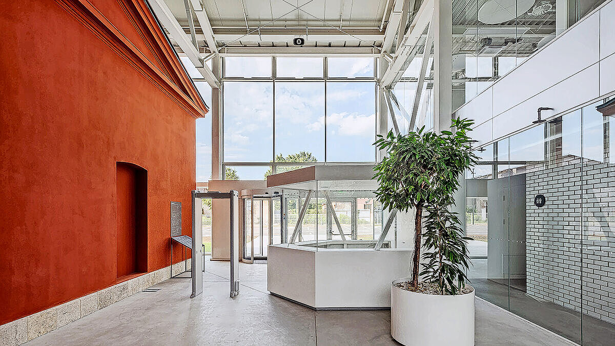 Le bâtiment rouge rénové trouve son pendant dans la construction claire, ouverte et transparente en acier et en verre.