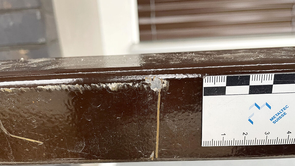 Écaillage de la peinture sur la main courante, traces de frottement, rayures et coupes réparées. Selon la fiche technique Metaltec Suisse TK 003, de tels défauts ne sont autorisés que dans une mesure très limitée et discrète.