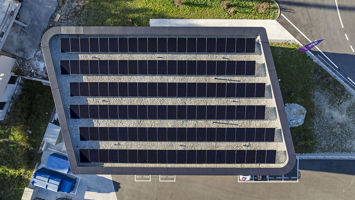 Draufsicht: Der trapezförmige Grundriss mit zwei in einem grosszügigen Radius verlaufenden Ecken. Das Flachdach ist ebenfalls mit PV-Modulen belegt.