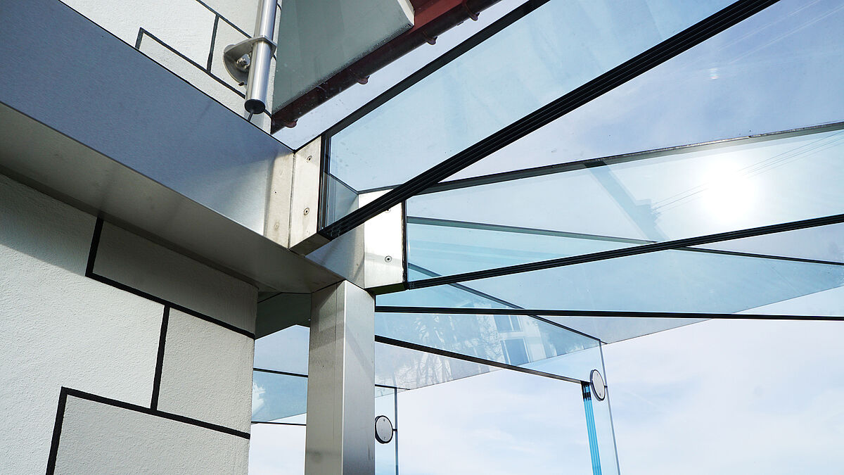 Bild: Mario RussiAnschluss an die Fassade. Alles aus Edelstahl: die Glasschuhprofile, die Verkleidungen der Wasserrinne und die Verkleidung des Dachwasserrohrs, das auch eine stützende Funktion wahrnimmt.