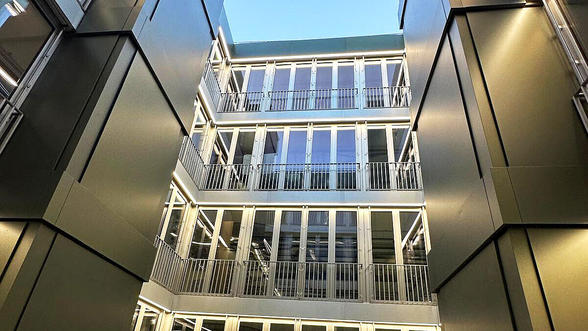 La façade de la cour intérieure avec toit à deux pans. Les revêtements en tôle vert olive des deux puits d’évacuation des fumées sont bien visibles. Photo : Surber Metallbau AG 