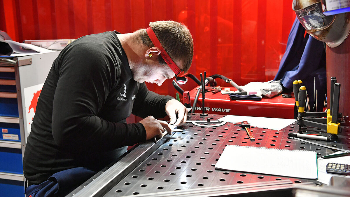 Lars Rotach se concentre sur sa pièce à son poste de travail.