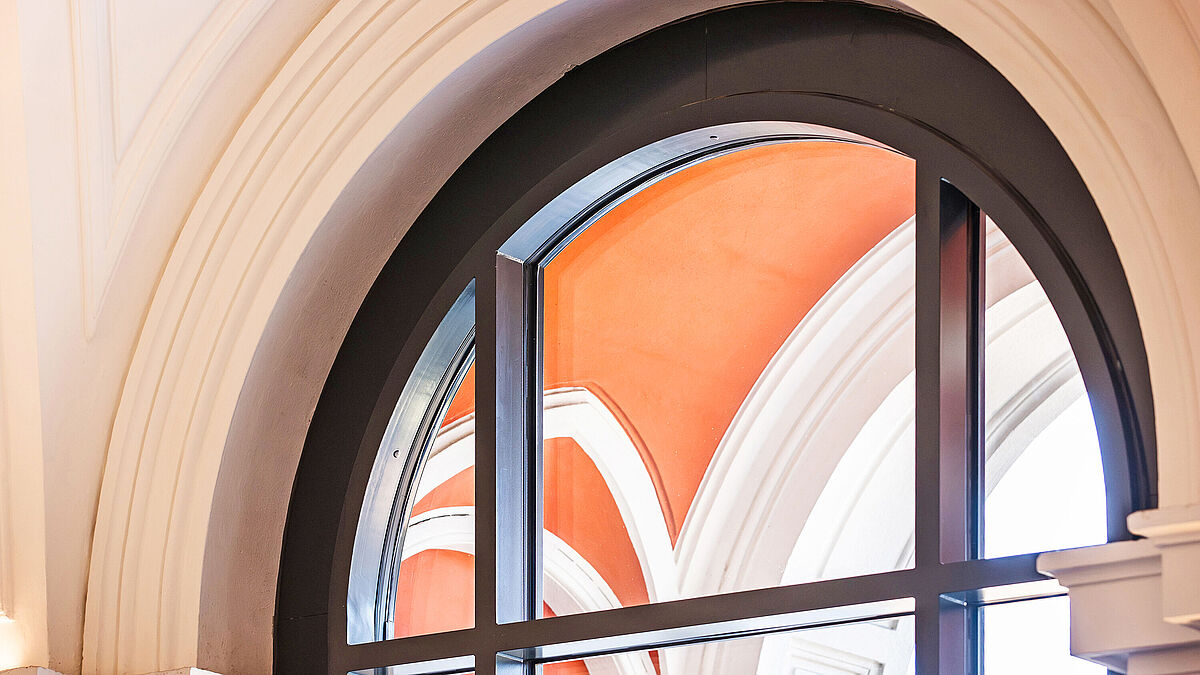 Neue Rundbogenfenster (Jansen Viss) integrieren sich nahtlos in die historische Fassade und bringen die ursprüngliche Architektur wieder zur Geltung.