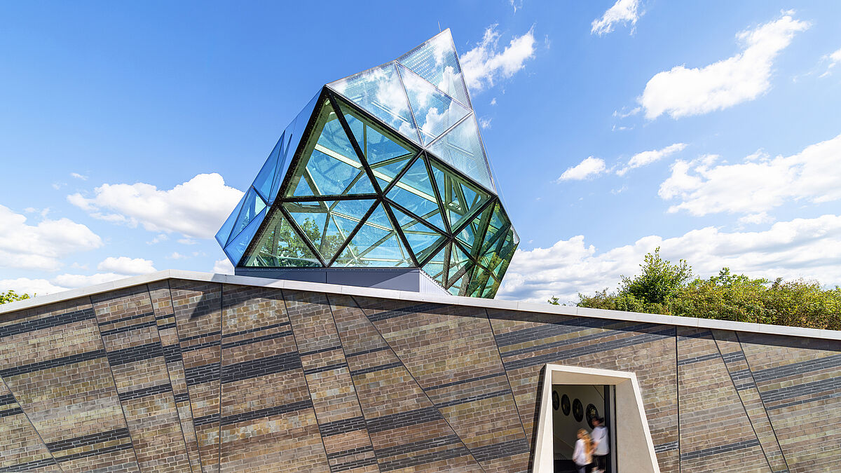 Eingangsbereich: Es entstand ein freistehendes Ausstellungsgebäude mit einem teilweise unterirdischen Sockelgeschoss. Darüber thront die ikonischen Glas-Stahl-Konstruktion.