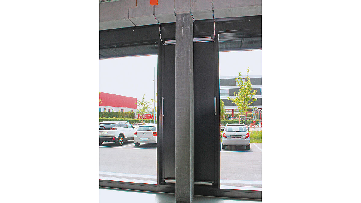 Innenansicht: Pfosten-Riegel-Fassade mit zwei RWA-Lochfenstern und montierten Fensterantrieben für die Nachströmung